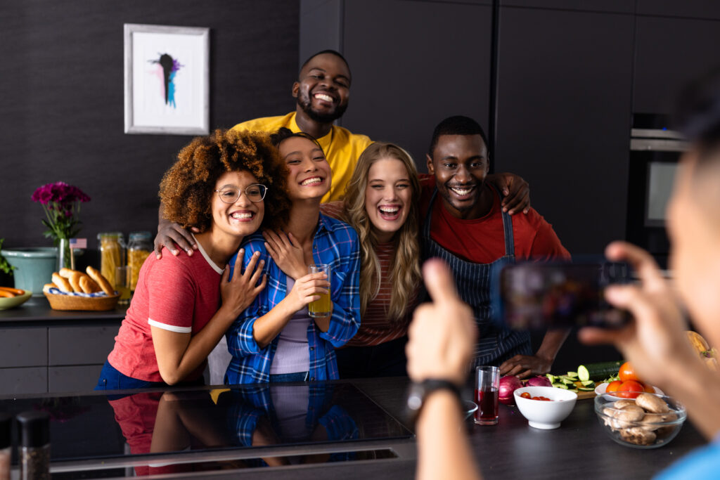 happy diverse group of friends taking photo with smartphone in kitchen